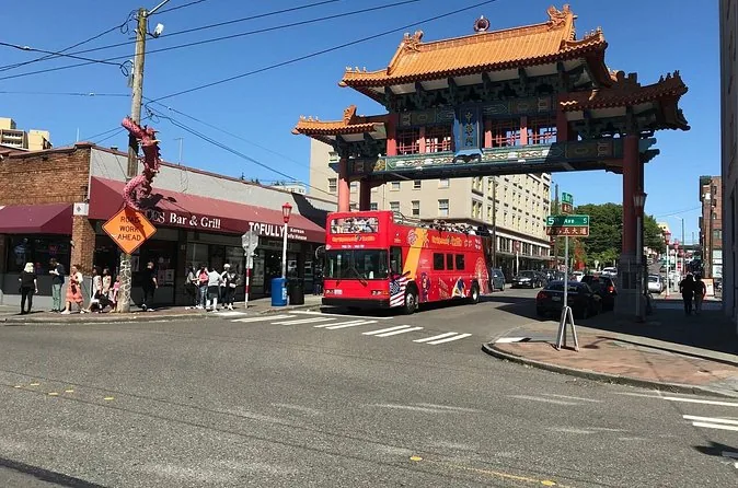 Ein roter Hop-on-Hop-off-Doppeldeckerbus fährt unter dem Chinatown-Tor hindurch
