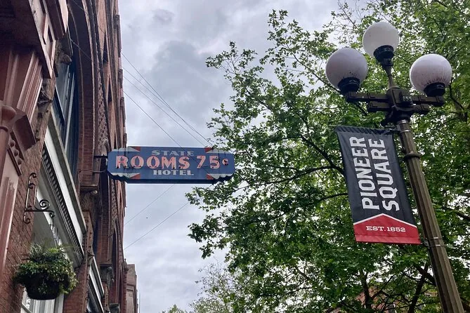 A Pioneer Square street banner on a lamp post next to an old Rooms 75c hotel sign